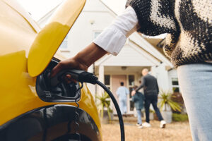 Woman charging her electrical vehicle outside her home.